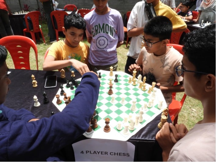Kids playing a four-player variant of chess at one of the light playing stalls